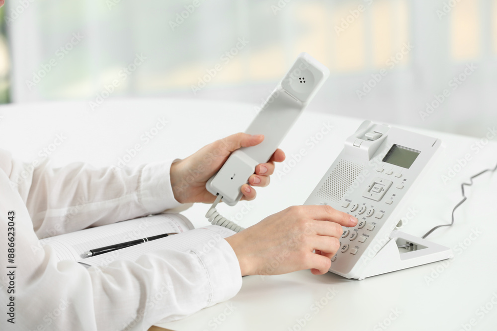 Fototapeta premium Assistant dialing number on telephone against blurred background, closeup