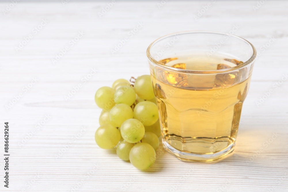 Ripe grapes and glass of tasty juice on white wooden table, closeup. Space for text Ripe grapes and glass of tasty juice on white wooden table, closeup. Space for text