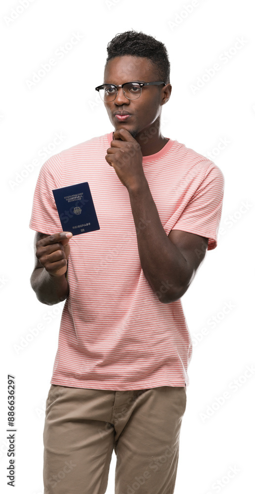 Young african american man holding german passport serious face thinking about question, very confused idea Young african american man holding german passport serious face thinking about question, very confused idea