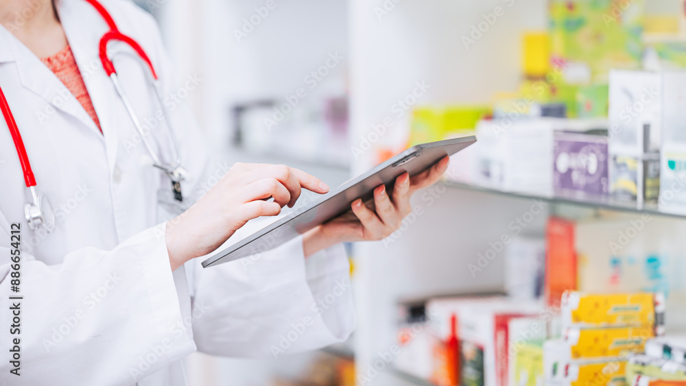 Pharmacist using online tablet checking drugs stock inventory in Pharmacy medicine business. Drugstore expire date stock monitor technology. Pharmacist using online tablet checking drugs stock inventory in Pharmacy medicine business. Drugstore expire date stock monitor technology.