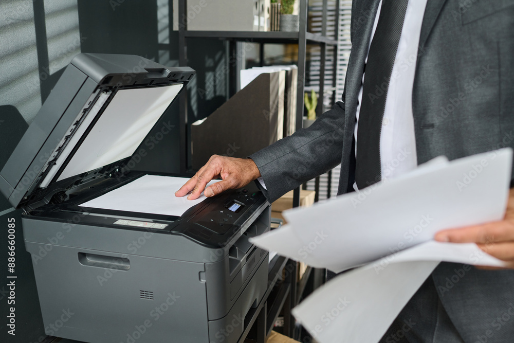 Cropped shot of male director of business company putting paper on copier screen of xerox machine to make copy of juridical document Cropped shot of male director of business company putting paper on copier screen of xerox machine to make copy of juridical document