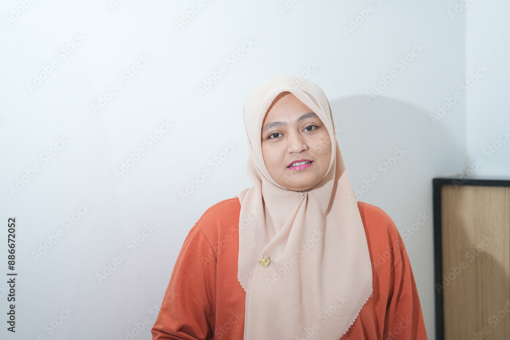 Fototapeta premium Portrait of a beautiful young Asian Muslim woman wearing a hijab being photographed in a studio