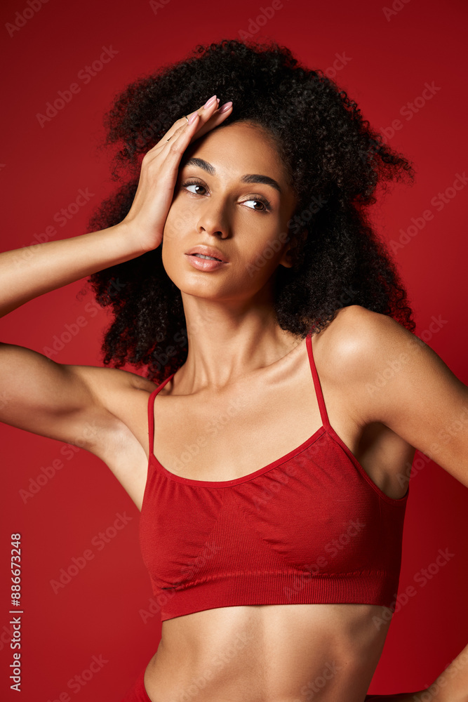 Vibrant young woman confidently poses in a striking red sports bra for a stylish photoshoot. Studio setting. Vibrant young woman confidently poses in a striking red sports bra for a stylish photoshoot. Studio setting.