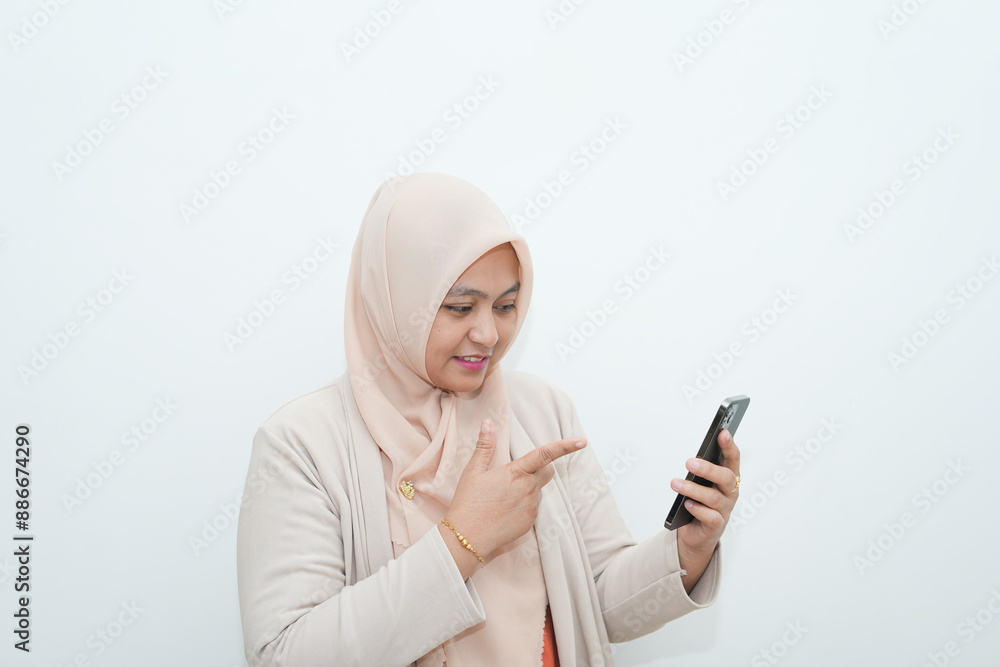 Portrait of a beautiful young Asian Muslim woman wearing hijab with happy gesture online with mobile phone Portrait of a beautiful young Asian Muslim woman wearing hijab with happy gesture online with mobile phone