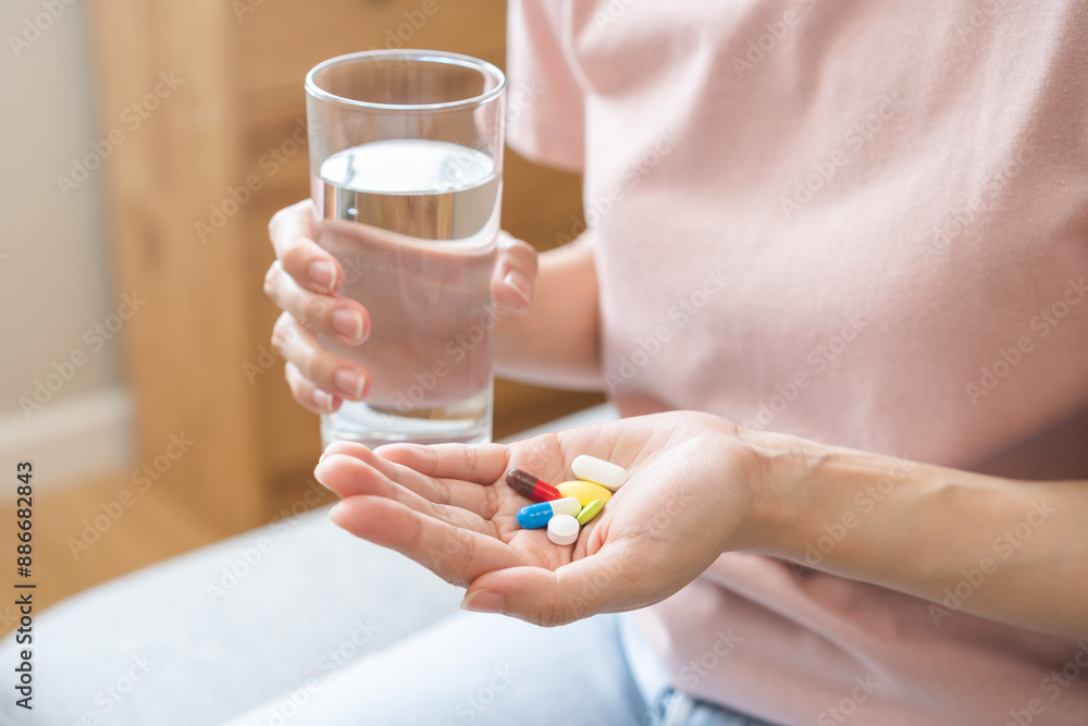Sick, asian young woman, girl hand holding pill capsule, painkiller medicine from stomach pain, head ache, pain for treatment, take drug or vitamin and glass of water at home, pharmacy and health care Sick, asian young woman, girl hand holding pill capsule, painkiller medicine from stomach pain, head ache, pain for treatment, take drug or vitamin and glass of water at home, pharmacy and health care