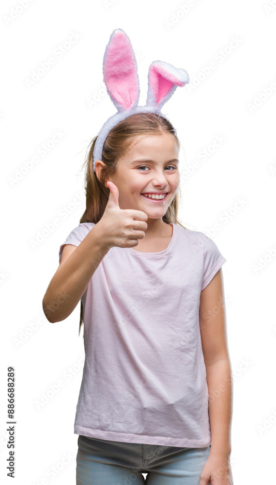 Young beautiful girl wearing easter bunny ears over isolated background doing happy thumbs up gesture with hand. Approving expression looking at the camera with showing success. Young beautiful girl wearing easter bunny ears over isolated background doing happy thumbs up gesture with hand. Approving expression looking at the camera with showing success.