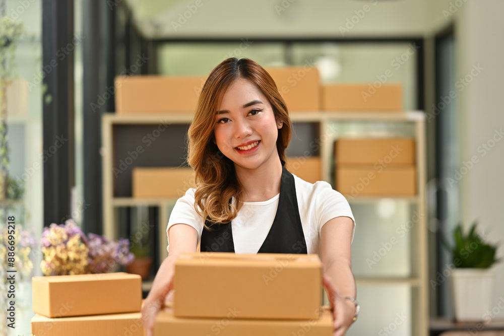 A smiling woman presents packages ready for delivery, highlighting the dedication and efficiency of her small business A smiling woman presents packages ready for delivery, highlighting the dedication and efficiency of her small business