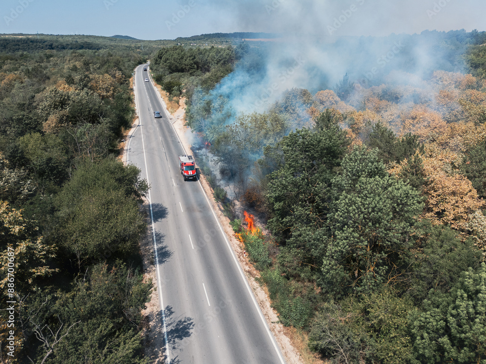Obraz premium Abnormal temperature records led to a dry summer and fires in Europe. European road with burning bushes due and smoke to a thrown cigarette butt