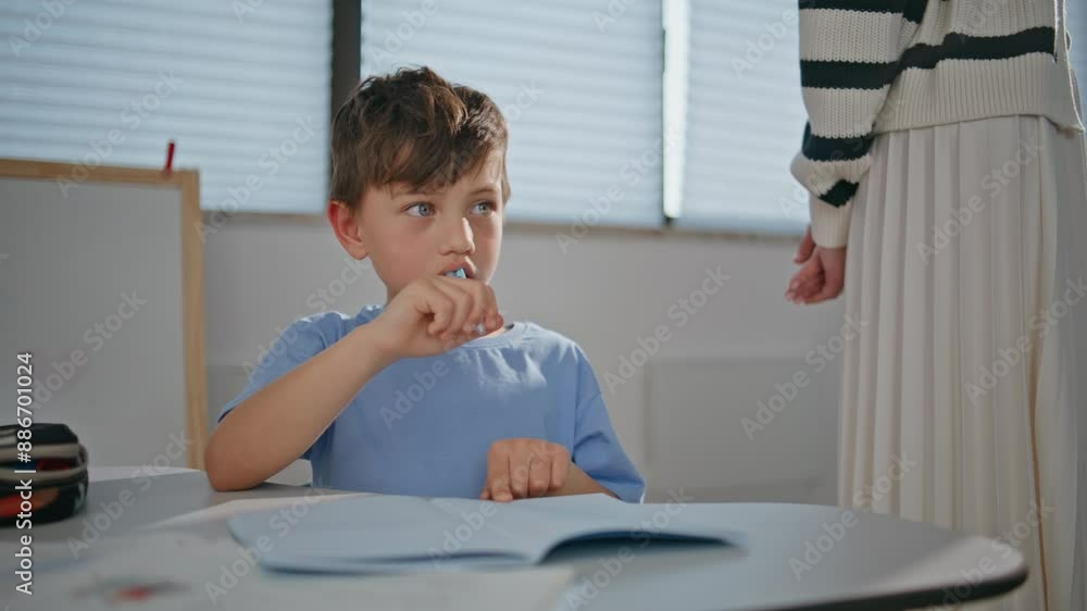 Small kid working diligently in notebook in elementary school class closeup Small kid working diligently in notebook in elementary school class closeup