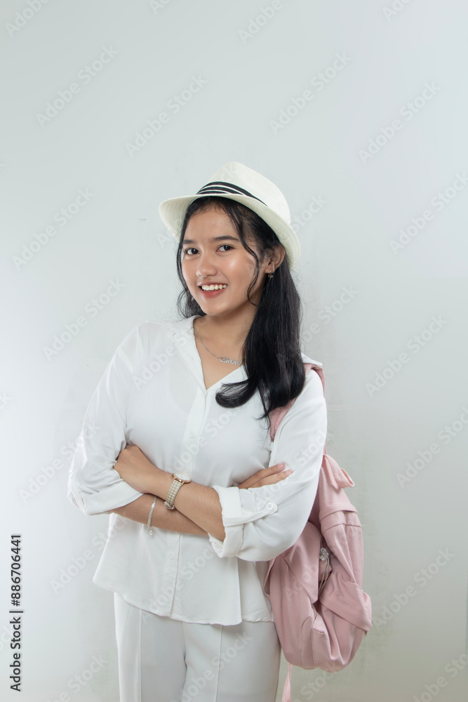 Beautiful young Asian woman tourist in straw hat standing confidently with arms crossed and looking at camera, young man with backpack, isolated on white Beautiful young Asian woman tourist in straw hat standing confidently with arms crossed and looking at camera, young man with backpack, isolated on white