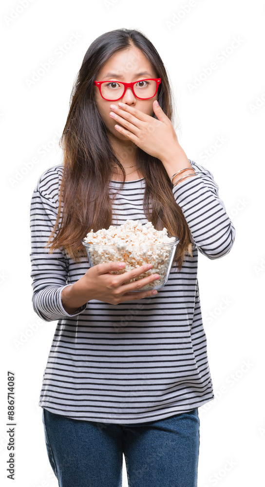 Young asian woman eating popcorn over isolated background cover mouth with hand shocked with shame for mistake, expression of fear, scared in silence, secret concept Young asian woman eating popcorn over isolated background cover mouth with hand shocked with shame for mistake, expression of fear, scared in silence, secret concept