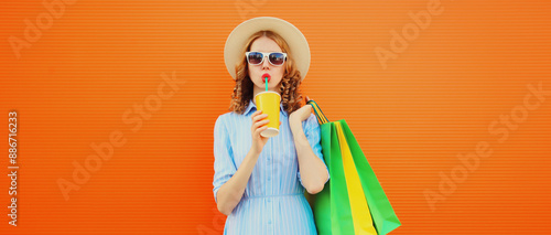 Fashion portrait of beautiful young woman with colorful shopping bags drinking juice in summer hat