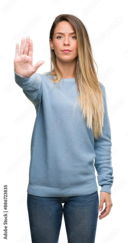 Beautiful young woman wearing sweater and jeans with open hand doing stop sign with serious and confident expression, defense gesture Beautiful young woman wearing sweater and jeans with open hand doing stop sign with serious and confident expression, defense gesture