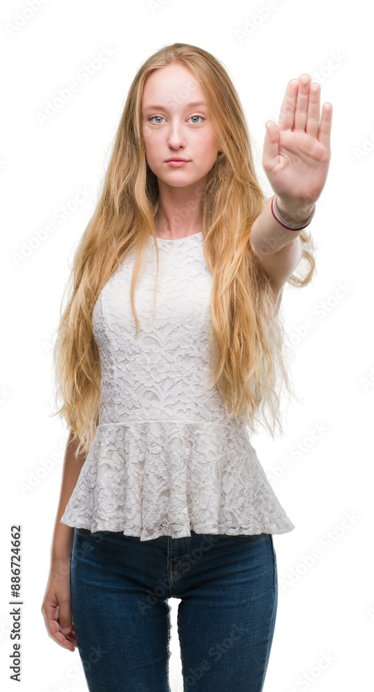 Blonde teenager woman with open hand doing stop sign with serious and confident expression, defense gesture Blonde teenager woman with open hand doing stop sign with serious and confident expression, defense gesture