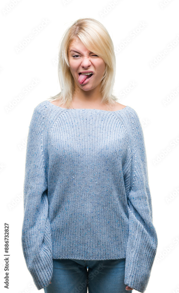 Young beautiful blonde woman wearing winter sweater over isolated background sticking tongue out happy with funny expression. Emotion concept. Young beautiful blonde woman wearing winter sweater over isolated background sticking tongue out happy with funny expression. Emotion concept.