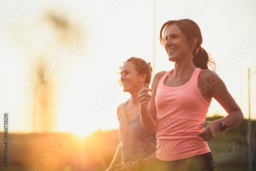 Photos Two athletic women in sportswear is jogging together