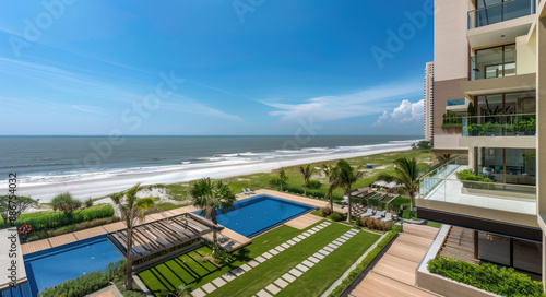 A stunning ocean front apartment building with wooden accents and glass, the lawn is lush green grass on one side of it. © Kien