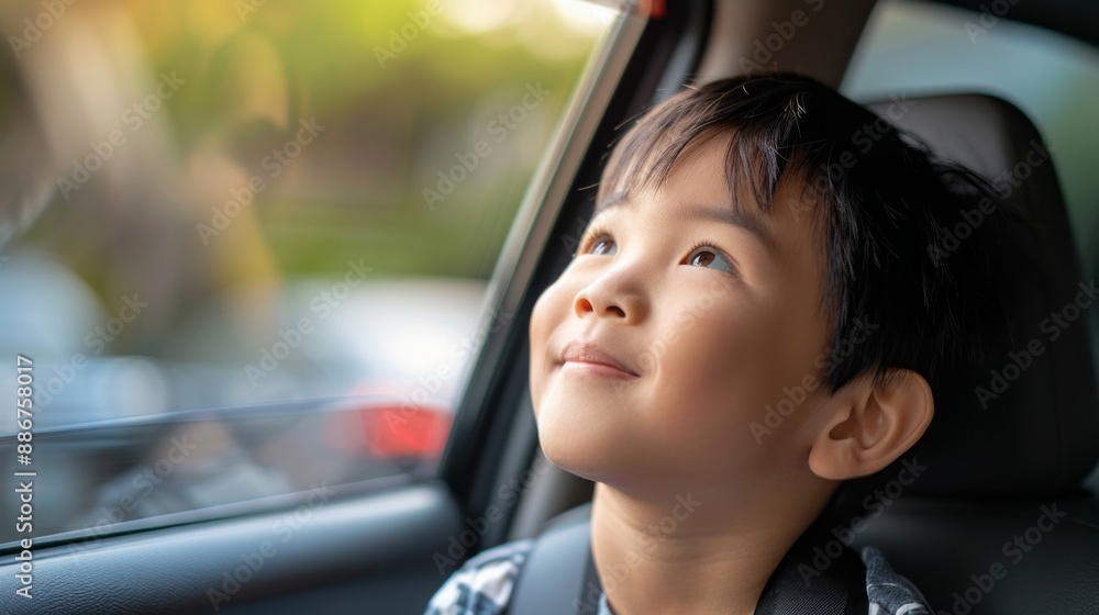 A young Asian boy sits in a car, looking out the window as rain falls A young Asian boy sits in a car, looking out the window as rain falls