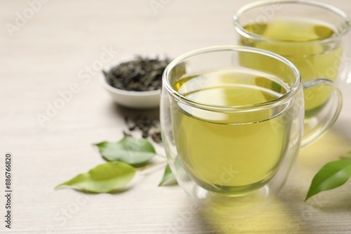 Refreshing green tea in cups and leaves on wooden table, closeup