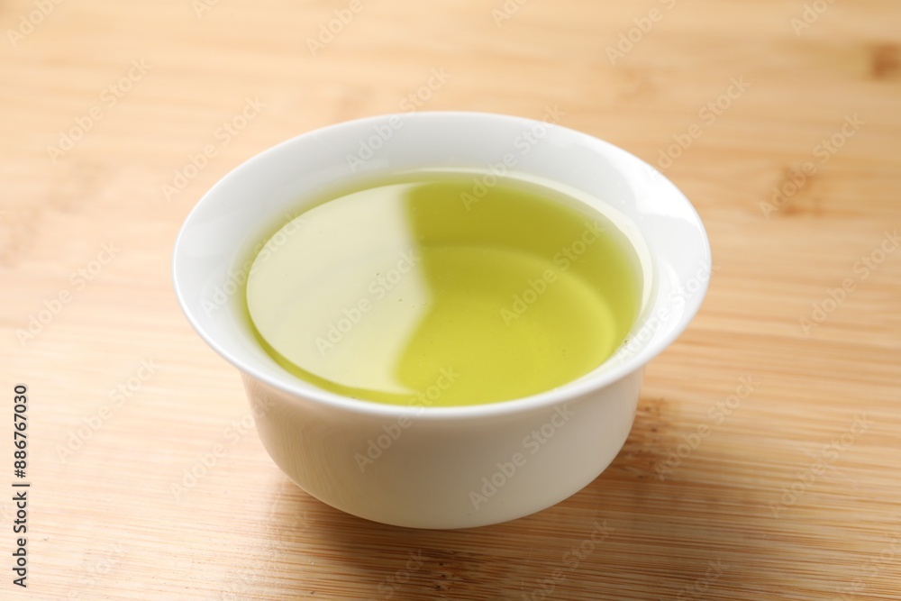 Refreshing green tea in cup on wooden table, closeup Refreshing green tea in cup on wooden table, closeup
