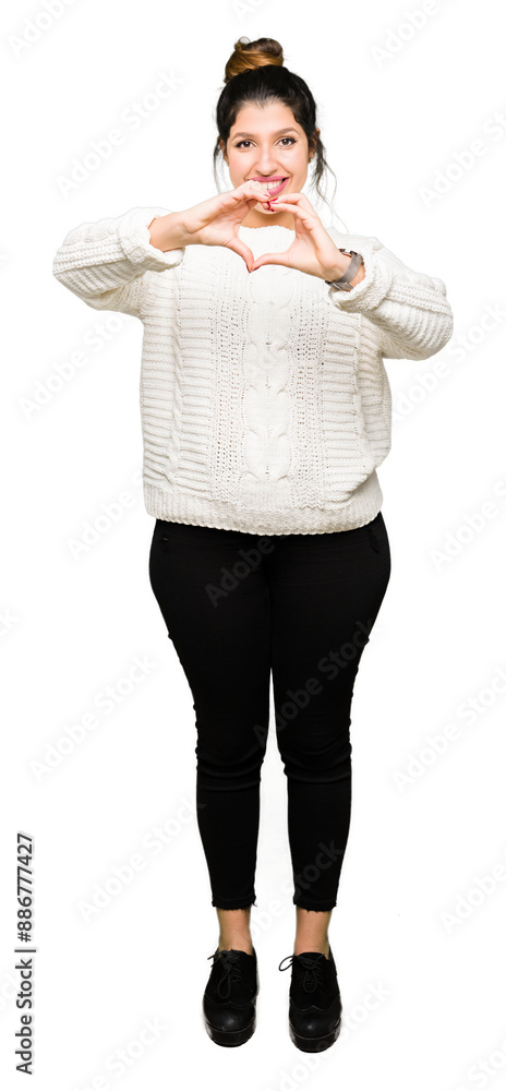 Young beautiful woman wearing winter sweater smiling in love showing heart symbol and shape with hands. Romantic concept. Young beautiful woman wearing winter sweater smiling in love showing heart symbol and shape with hands. Romantic concept.