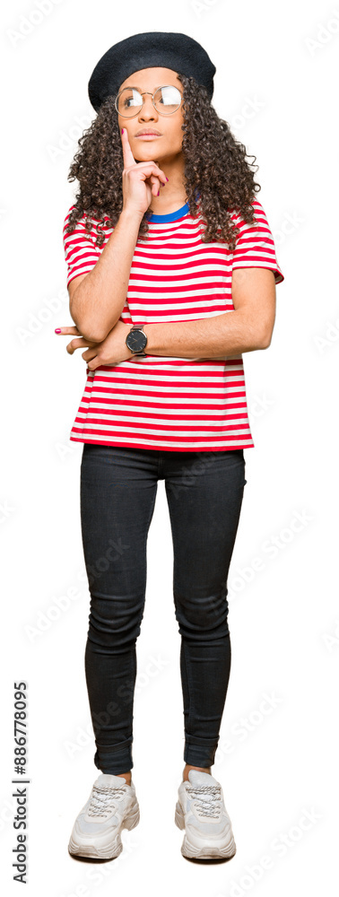 Obraz premium Young beautiful woman with curly hair wearing glasses and fashion beret with hand on chin thinking about question, pensive expression. Smiling with thoughtful face. Doubt concept.