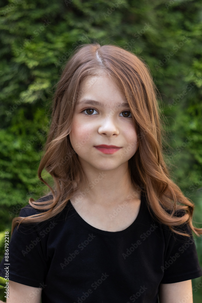 Fashion portrait of a beautiful little girl with makeup and hairstyle outdoors