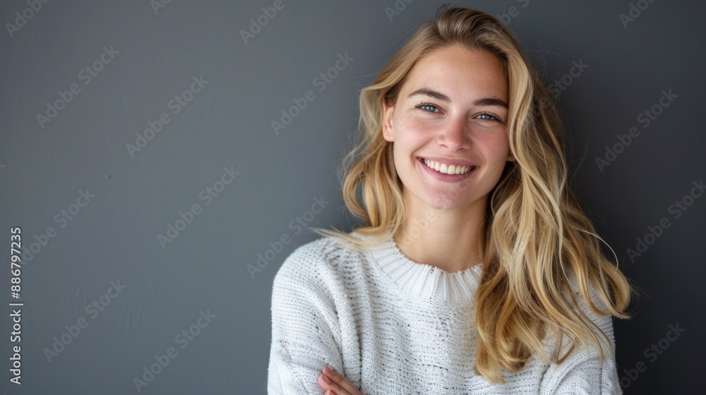 Smiling blonde woman in a sweater gray background Smiling blonde woman in a sweater gray background