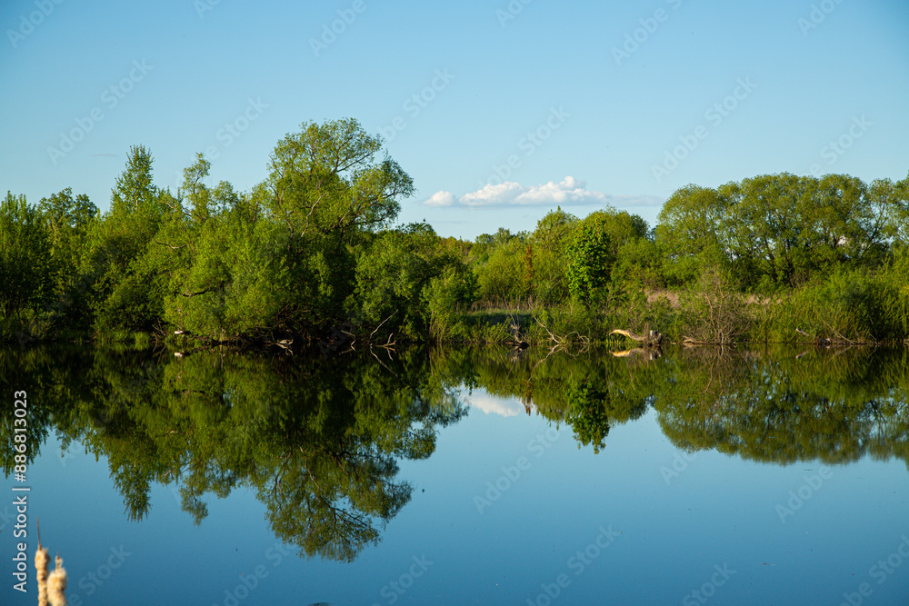 The landscape is serene, featuring water reflection and lush green trees in a tranquil setting The landscape is serene, featuring water reflection and lush green trees in a tranquil setting