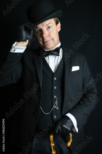 Polite British Gentleman in Formal Suit and Leather Gloves Doffing Bowler Hat Respectfully. Professional Hospitality of Butler or Hotel Doorman.