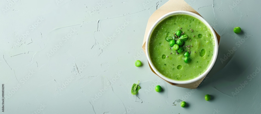 Mock-up of a vegan food delivery concept showcasing a green cream soup in a paper package or disposable cup with pea and spirulina, with copy space image. Mock-up of a vegan food delivery concept showcasing a green cream soup in a paper package or disposable cup with pea and spirulina, with copy space image.
