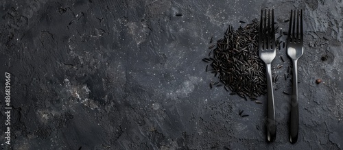 A top-down picture featuring wild black rice on a black background with a fork, providing space for additional images. photo