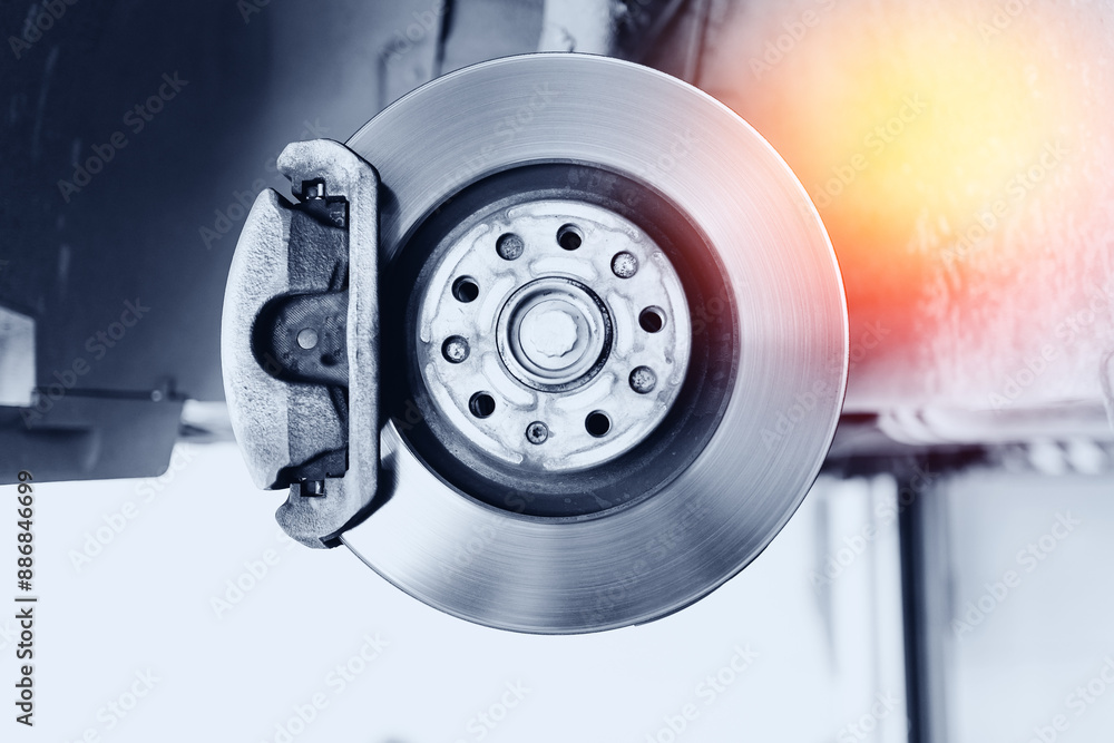 Closeup steel brake disk and detail of wheel hub with sunlight. Concept replacing wheel pads in garage car service Closeup steel brake disk and detail of wheel hub with sunlight. Concept replacing wheel pads in garage car service