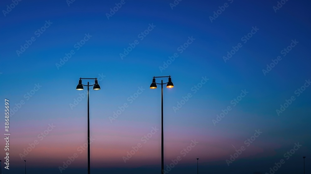 Silhouette of electric lamp posts against clear blue twilight sky Silhouette of electric lamp posts against clear blue twilight sky