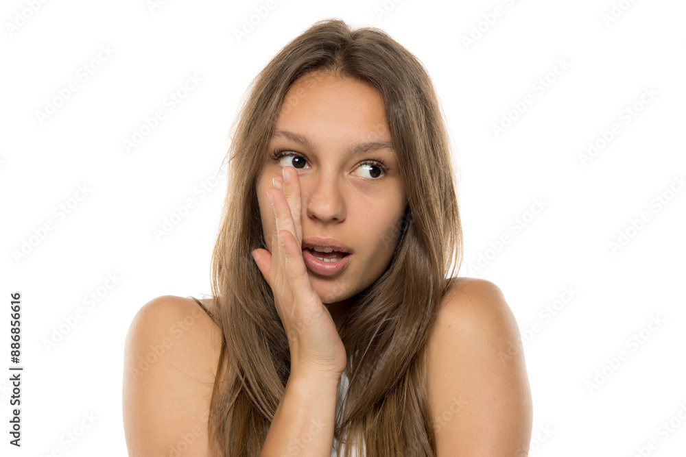 Young woman is holding hand near mouth and telling a secret on a white background Young woman is holding hand near mouth and telling a secret on a white background