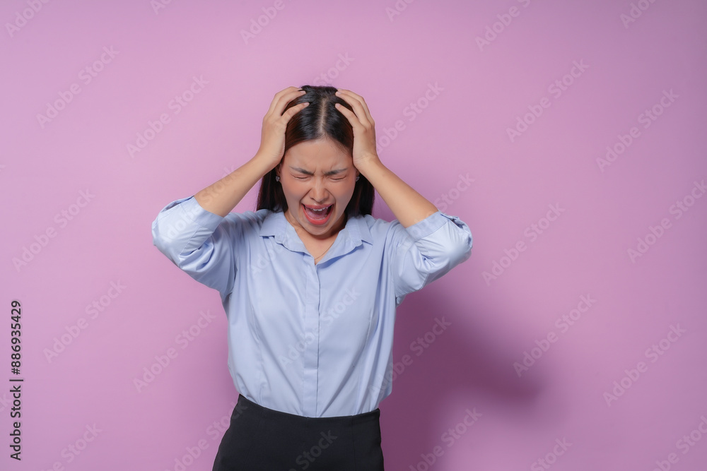 Young asian businesswoman is having a mental breakdown and screaming, holding her head with her hands. She is feeling overwhelmed, stressed and frustrated Young asian businesswoman is having a mental breakdown and screaming, holding her head with her hands. She is feeling overwhelmed, stressed and frustrated