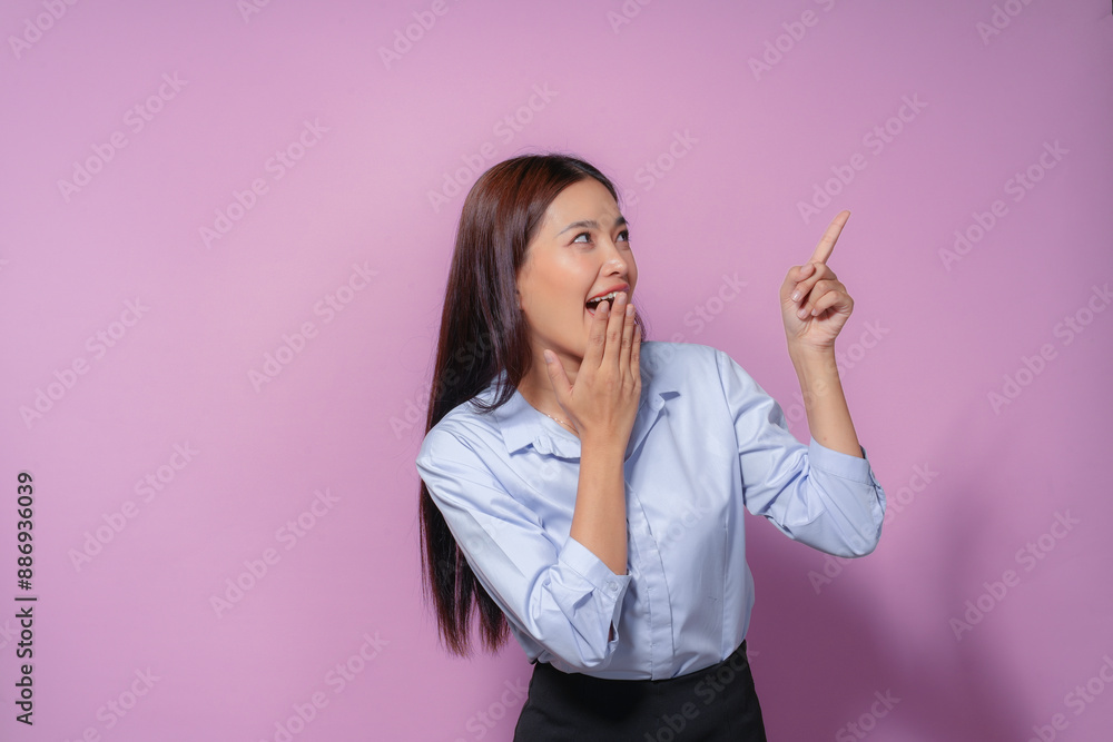 Asian businesswoman is covering her mouth with her hand and pointing with the other one, surprised by an unexpected promotion Asian businesswoman is covering her mouth with her hand and pointing with the other one, surprised by an unexpected promotion