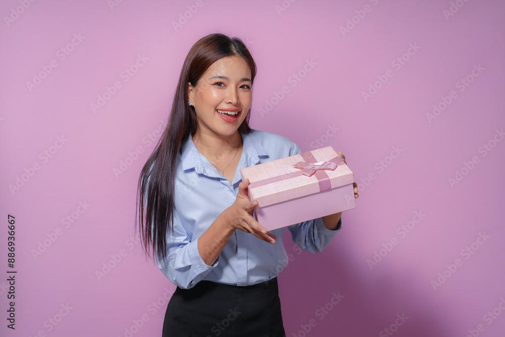 Excited woman holding pink gift box with purple ribbon, smiling happily. Perfect for conveying joy and generosity Excited woman holding pink gift box with purple ribbon, smiling happily. Perfect for conveying joy and generosity