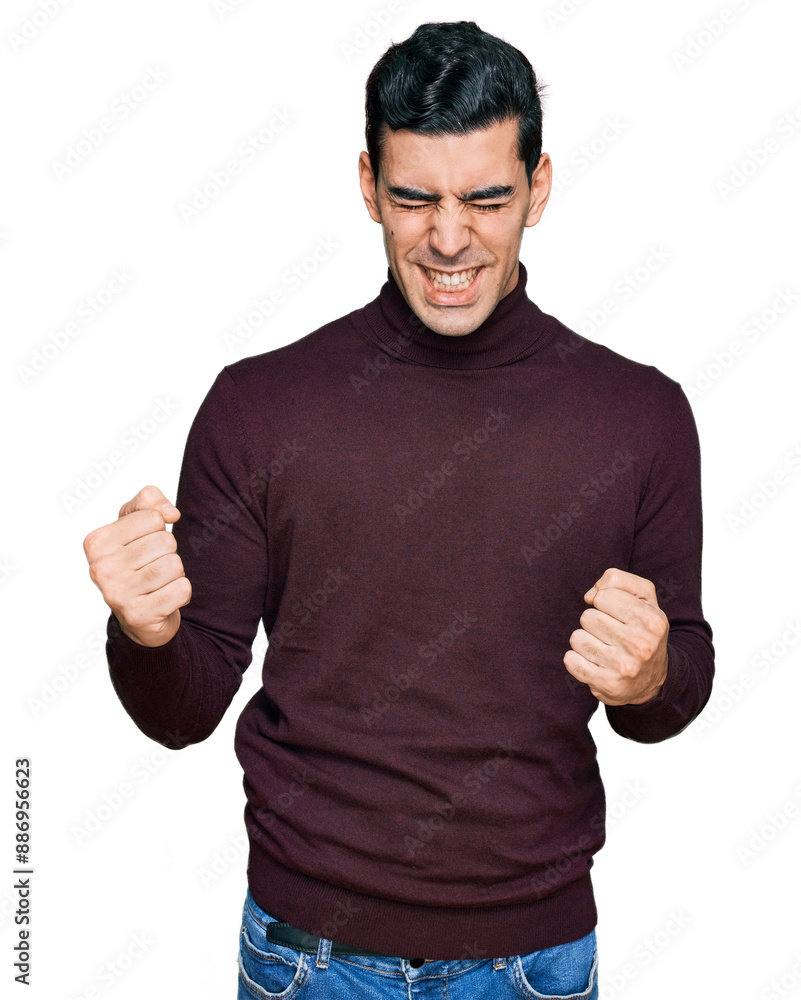 Handsome hispanic man wearing casual turtleneck sweater very happy and excited doing winner gesture with arms raised, smiling and screaming for success. celebration concept. Handsome hispanic man wearing casual turtleneck sweater very happy and excited doing winner gesture with arms raised, smiling and screaming for success. celebration concept.