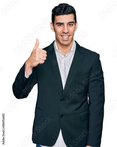 Handsome hispanic man wearing business clothes doing happy thumbs up gesture with hand. approving expression looking at the camera showing success.