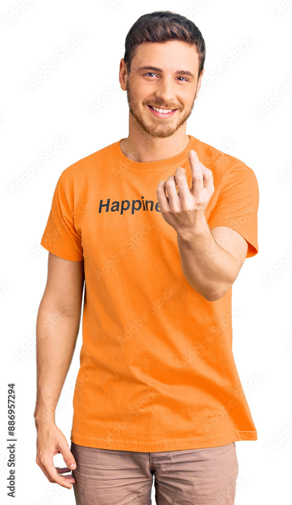 Handsome young man with bear wearing tshirt with happiness word message beckoning come here gesture with hand inviting welcoming happy and smiling Handsome young man with bear wearing tshirt with happiness word message beckoning come here gesture with hand inviting welcoming happy and smiling