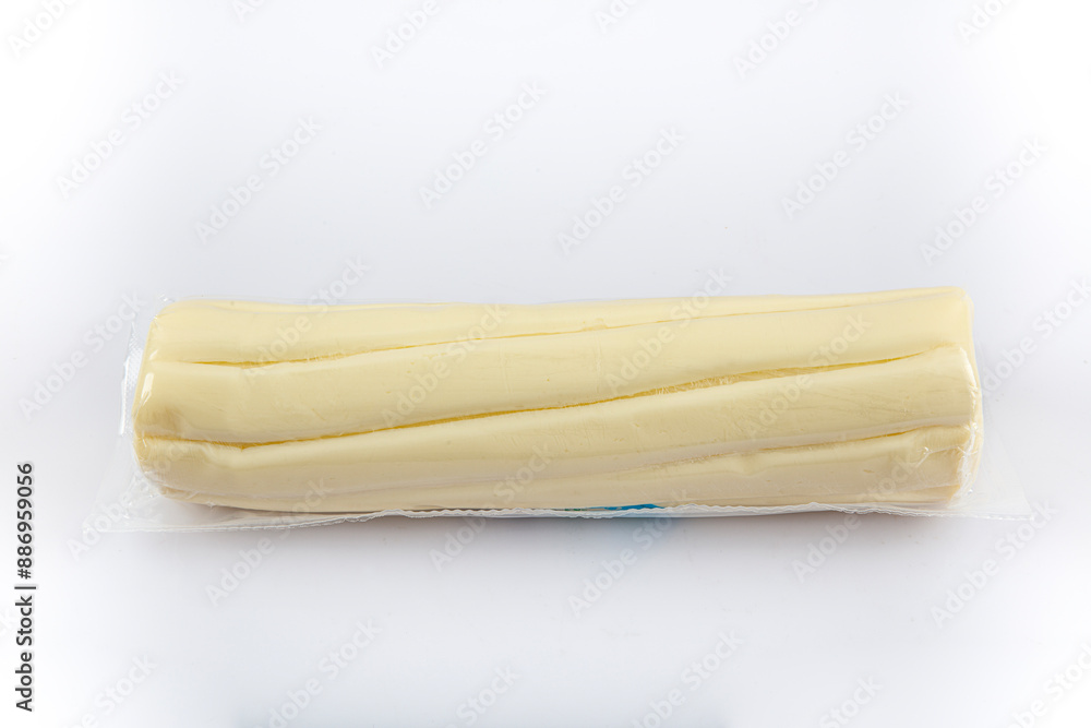 A stick of butter isolated on a white studio background. One kilo of Butter in plastic packaging. A stick of butter isolated on a white studio background. One kilo of Butter in plastic packaging.