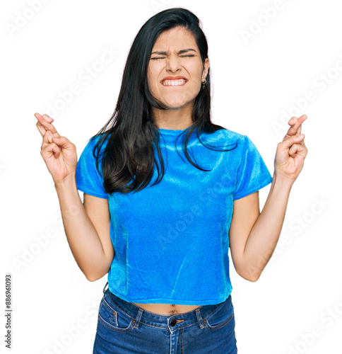 Young hispanic woman wearing casual clothes gesturing finger crossed smiling with hope and eyes closed. luck and superstitious concept.