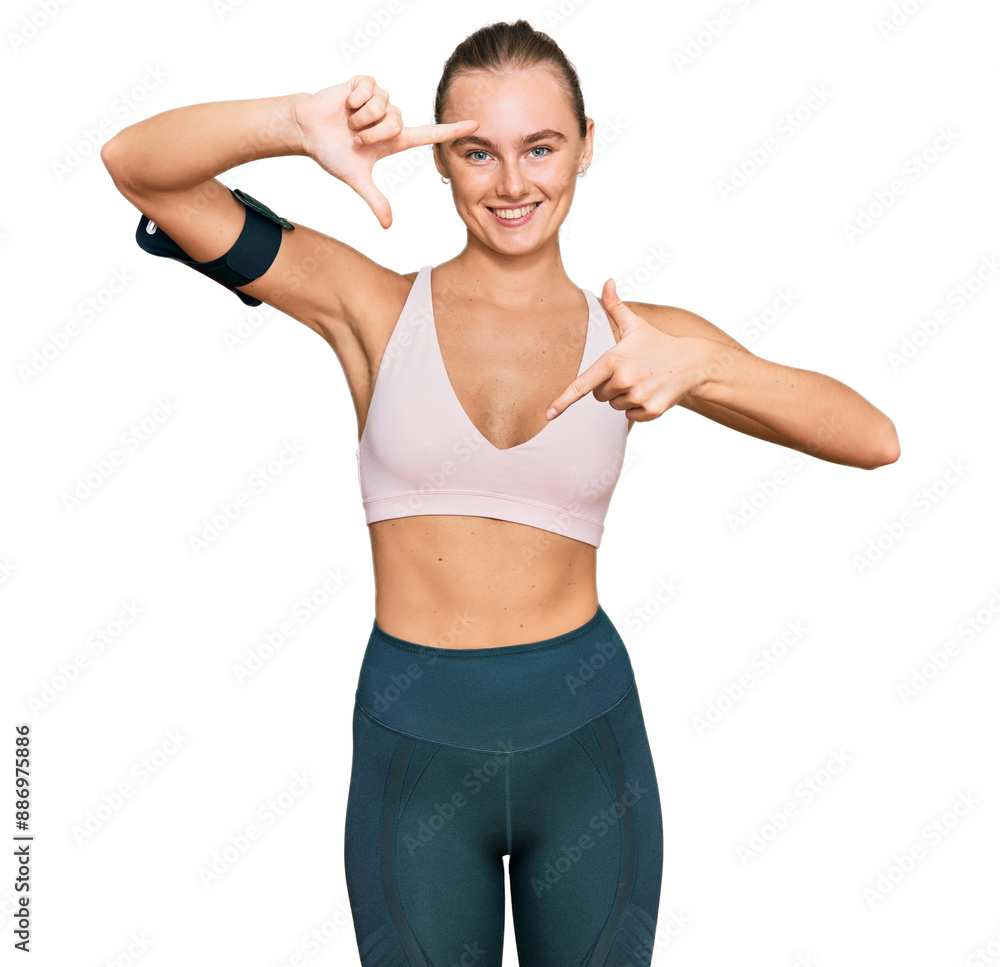 Beautiful young blonde woman wearing sportswear and arm band smiling making frame with hands and fingers with happy face. creativity and photography concept. Beautiful young blonde woman wearing sportswear and arm band smiling making frame with hands and fingers with happy face. creativity and photography concept.