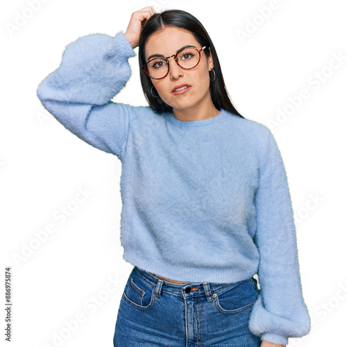 Young hispanic woman wearing casual clothes and glasses confuse and wonder about question. uncertain with doubt, thinking with hand on head. pensive concept. photo