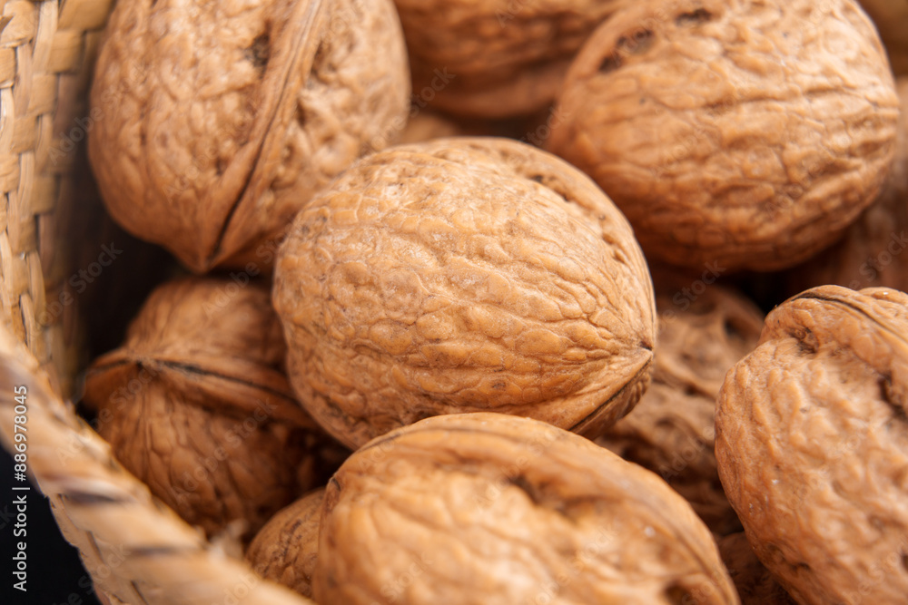 Mature whole walnuts with textured hard shells in a rustic wicker bowl. Macro shot. Healthy organic nuts Mature whole walnuts with textured hard shells in a rustic wicker bowl. Macro shot. Healthy organic nuts