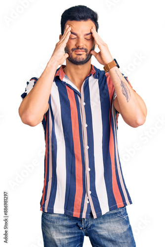 Young handsome hispanic man wearing casual summer shirt suffering from headache desperate and stressed because pain and migraine. hands on head.