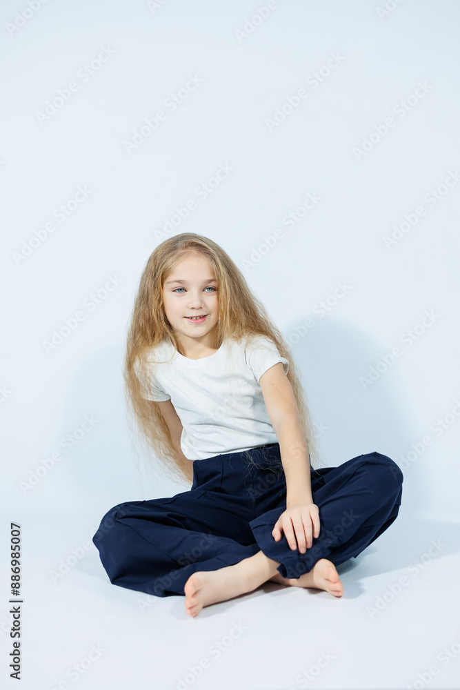 Teenage girl with long hair in white t-shirt and blue jeans and smiling isolated on gray background. Stylish clothes for girls. Teenage girl with long hair in white t-shirt and blue jeans and smiling isolated on gray background. Stylish clothes for girls.