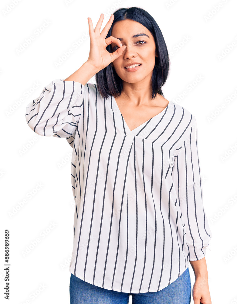 Young beautiful latin woman wearing casual clothes smiling happy doing ok sign with hand on eye looking through fingers Young beautiful latin woman wearing casual clothes smiling happy doing ok sign with hand on eye looking through fingers