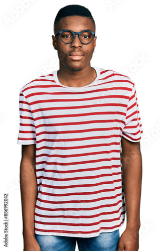 Young african american man wearing casual t shirt and glasses relaxed with serious expression on face. simple and natural looking at the camera.